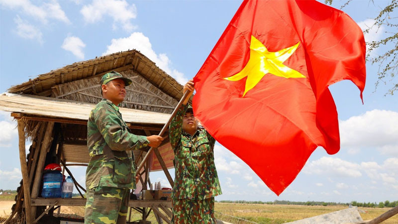 Quân nhân đứng dưới lá cờ đỏ sao vàng phấp phới