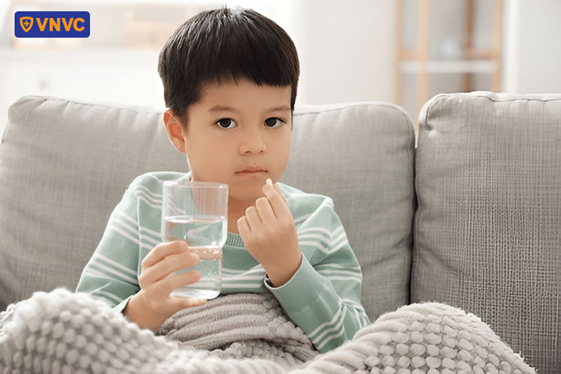 Bé trai uống thuốc theo chỉ định của bác sĩ để giảm triệu chứng và nhanh hồi phục
