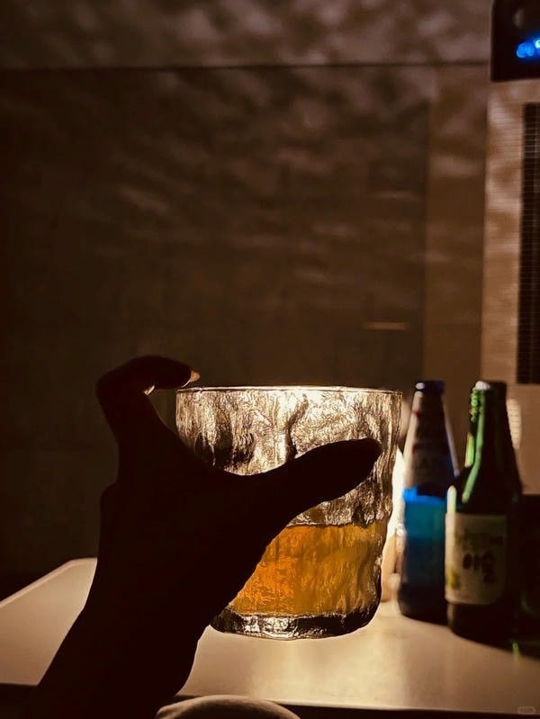 Hình ảnh một người thanh niên ngồi quay lưng, vai gầy guộc bên bàn nhậu đơn độc, thể hiện sự cô đơn sâu sắc.