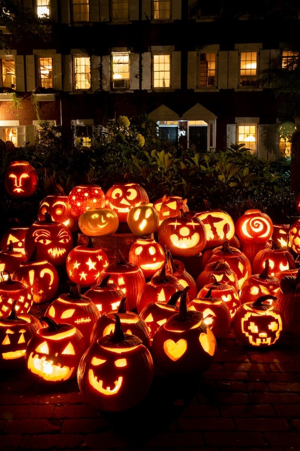Một người hóa trang thành bí ngô Jack-o'-lantern khổng lồ, đứng trong khung cảnh lễ hội Halloween nhộn nhịp